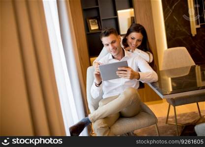 Young couple relaxing at home and using digital tablet in the living room by the window