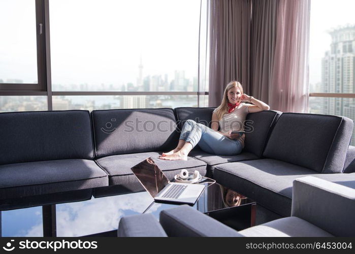 Young couple relaxing at home using tablet computer reading in the living room near the window on the sofa couch.