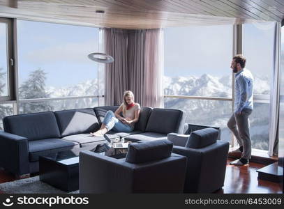 Young couple relaxing at home using tablet computer reading in the living room near the window on the sofa couch.