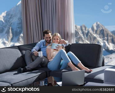 Young couple relaxing at home using tablet computers reading in the living room on the sofa couch.