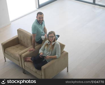 Young couple relaxing at luxurious home with tablet computers reading in the living room on the sofa couch.