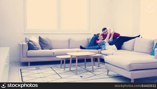 Young couple relaxing at luxurious home with tablet computers reading in the living room on the sofa couch.