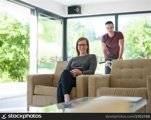 Young couple relaxing at luxurious home woman using tablet computers while man preparing for exercise