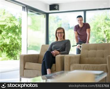 Young couple relaxing at luxurious home woman using tablet computers while man preparing for exercise