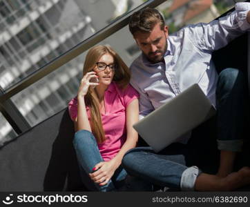 Young couple relaxing at luxury home using laptop computer reading in the living room on the sofa couch.