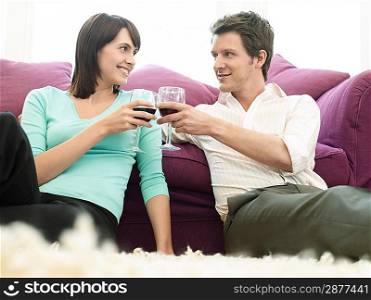 Young couple relaxing on sofa toasting with wine