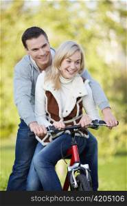 Young couple rides a bicycle in the park
