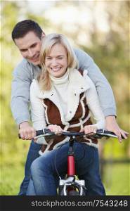 Young couple rides a bicycle in the park
