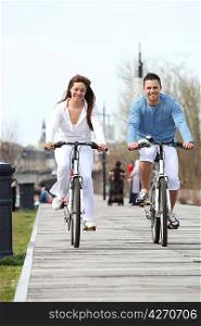 Young couple riding bikes along a boardwalk