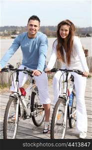 Young couple riding bikes along a river