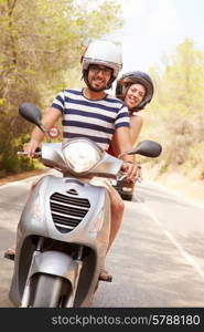 Young Couple Riding Motor Scooter Along Country Road