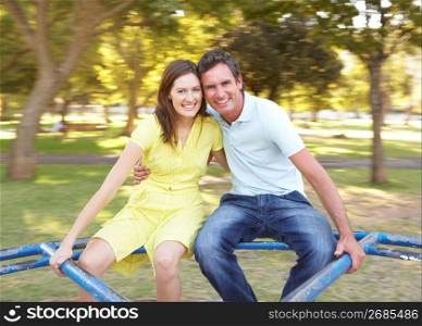 Young Couple Riding On Roundabout In Park