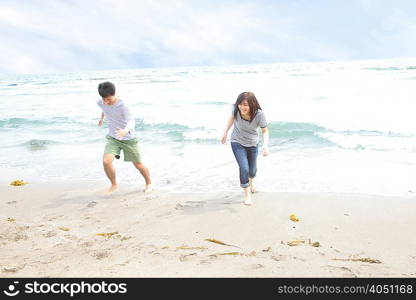Young couple running away from tide