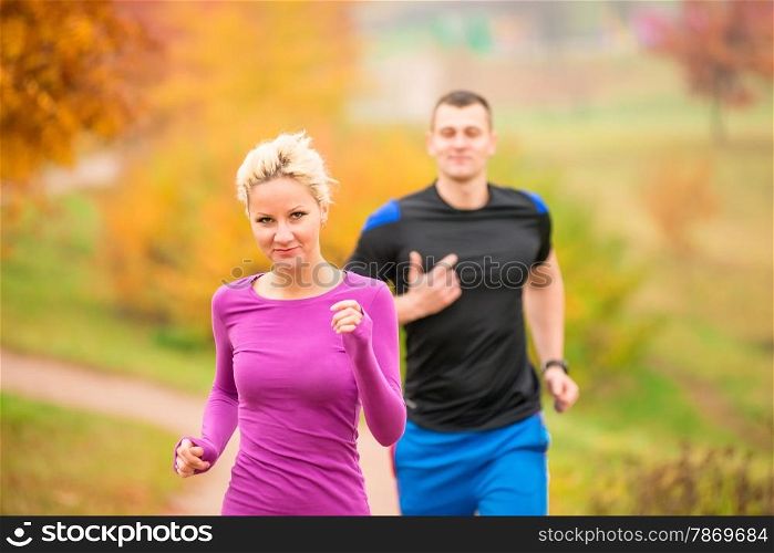 young couple running in the park in autumn morning