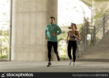 Young couple running in urban enviroment at sunny day