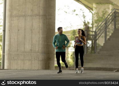 Young couple running in urban enviroment at sunny day