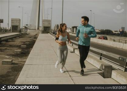 Young couple running in urban enviroment at sunny day