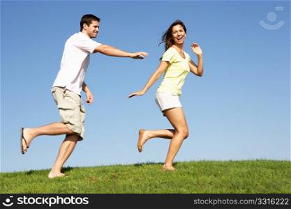 Young couple running through field