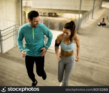 Young couple running up stairs outdoors in urban environment
