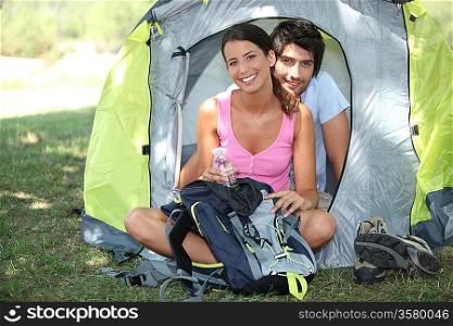 Young couple sat by tent