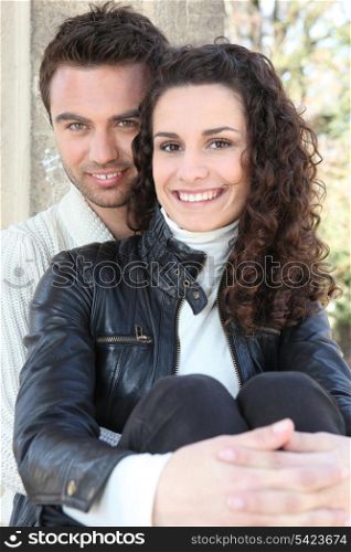 Young couple sat by wall