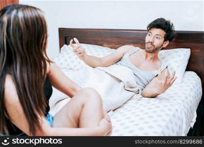 Young couple screaming at each other in bed. Husband arguing with his wife in bed, Concept of couple problems in bed. Upset woman with husband sitting on bed