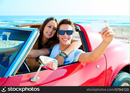 young couple selfie happy in a red convertible car at the beach