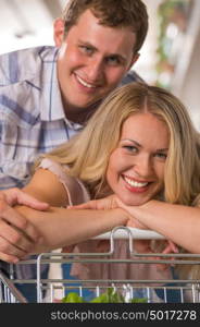 Young couple shopping at supermarket - hugging and leaning on trolley