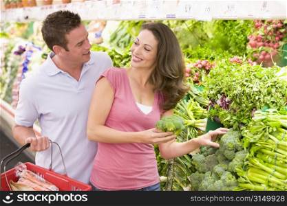 Young couple shopping for broccoli at a grocery store