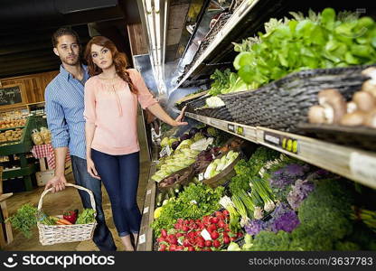 Young couple shopping for vegetables in supermarket