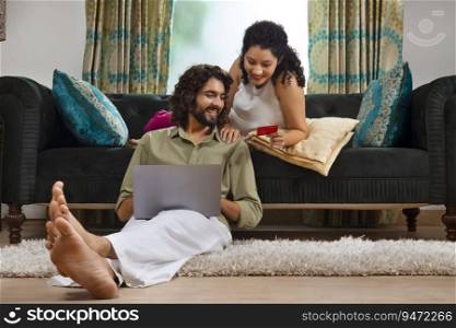 Young couple shopping online through laptop using credit card at home