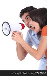 Young couple shouting into a loudspeaker