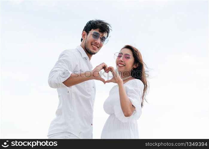 Young couple shows heart shape hand gesture on the beach in summer.. Young couple shows heart shape hand gesture.