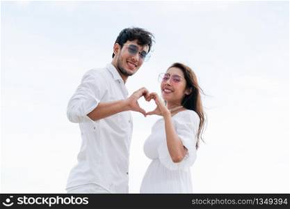 Young couple shows heart shape hand gesture on the beach in summer.. Young couple shows heart shape hand gesture.