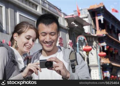 Young couple sightseeing, looking at digital camera.