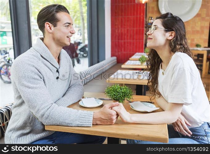 Young couple sit at little table in a cafe.