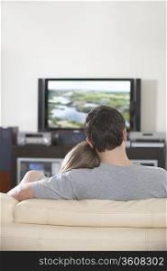 Young couple sit watching television