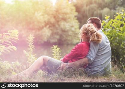 Young couple sitting amidst plants at lakeshore
