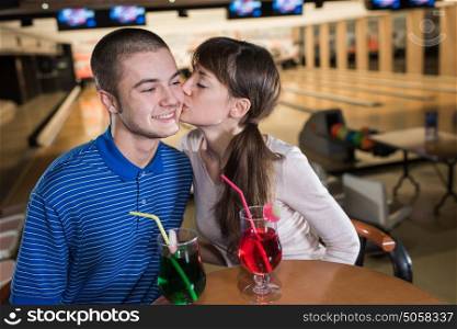 young couple sitting and kissing at the bowling bar