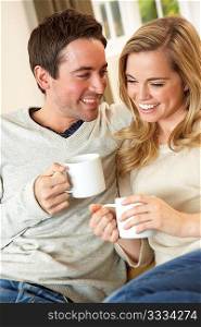 Young couple sitting and relaxing on sofa with cup in hand