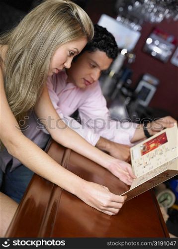 Young couple sitting at a bar counter and looking at a menu