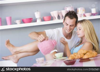 Young couple sitting at a table flirting and having tea