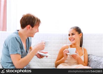 Young couple sitting at couch and drinking coffee&#xA;