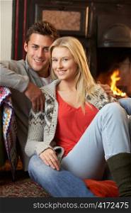 Young couple sitting by open fire