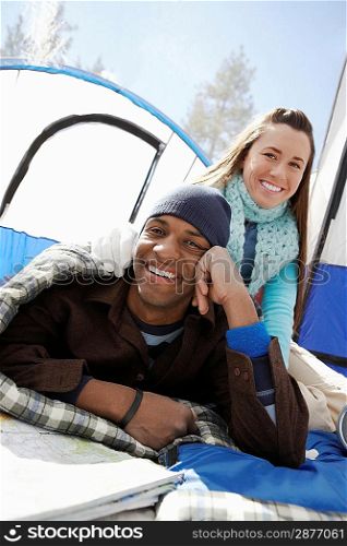 Young couple sitting by tent at campsite