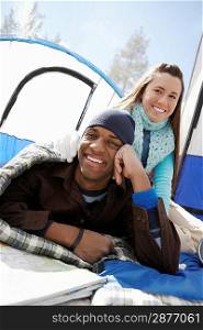 Young couple sitting by tent at campsite
