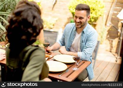 Young couple sitting by the wooden table in the backyard