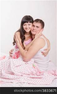 Young couple sitting in bed and hugging each other