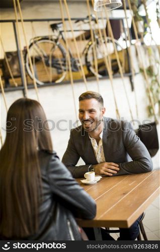 Young couple sitting in cafe, talking and drinking coffee