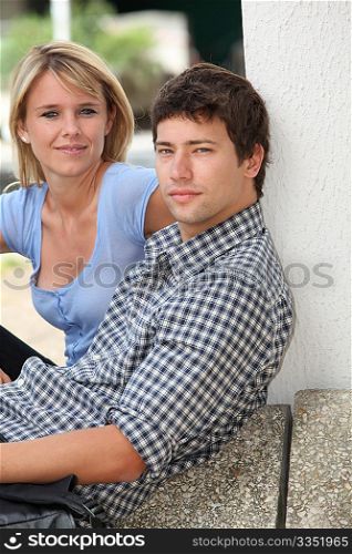 Young couple sitting in campus yard